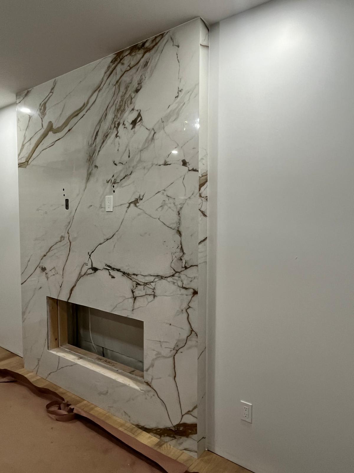 Angled view of a full-height calacatta marble fireplace wall