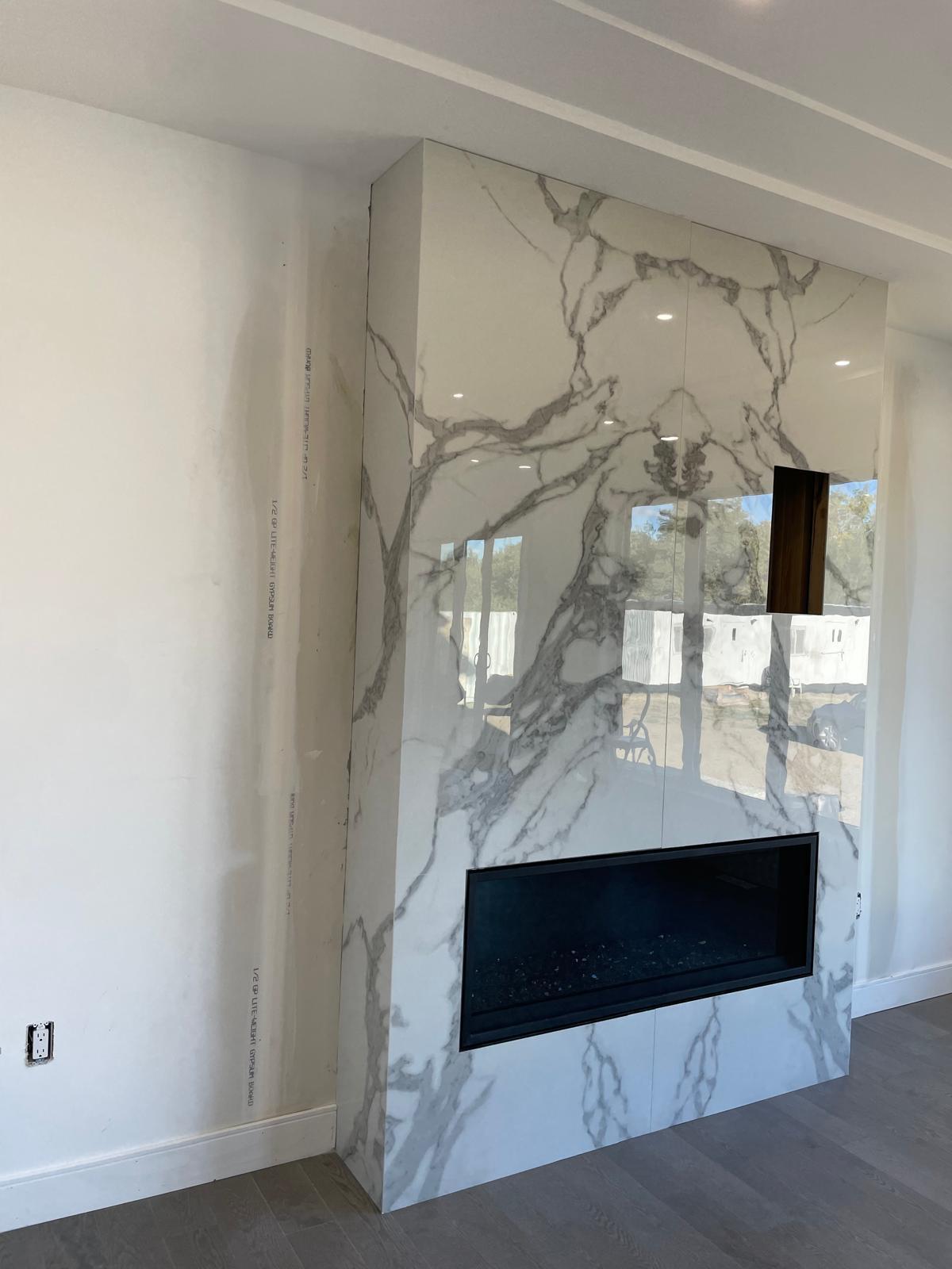 Angled view of a bookmatched white marble fireplace feature wall